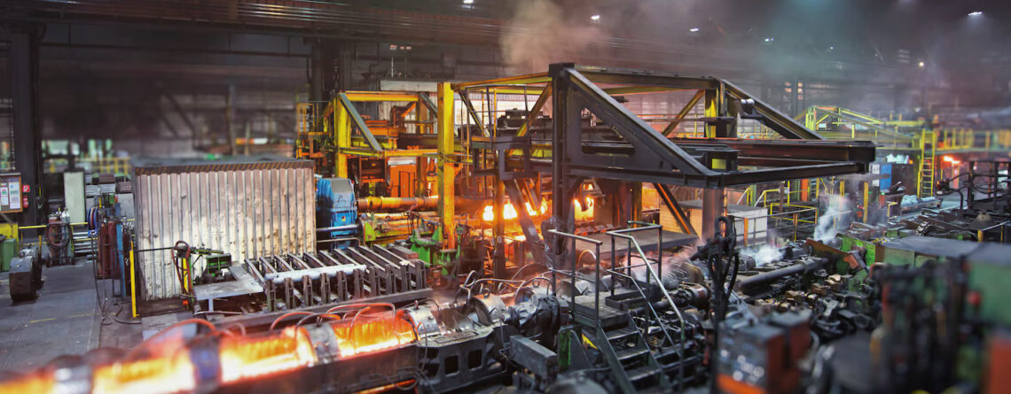 Usina siderúrgica com máquinas em operação, mostrando o ambiente desafiador onde os sistemas de secagem Leister ajudam a manter a confiabilidade elétrica