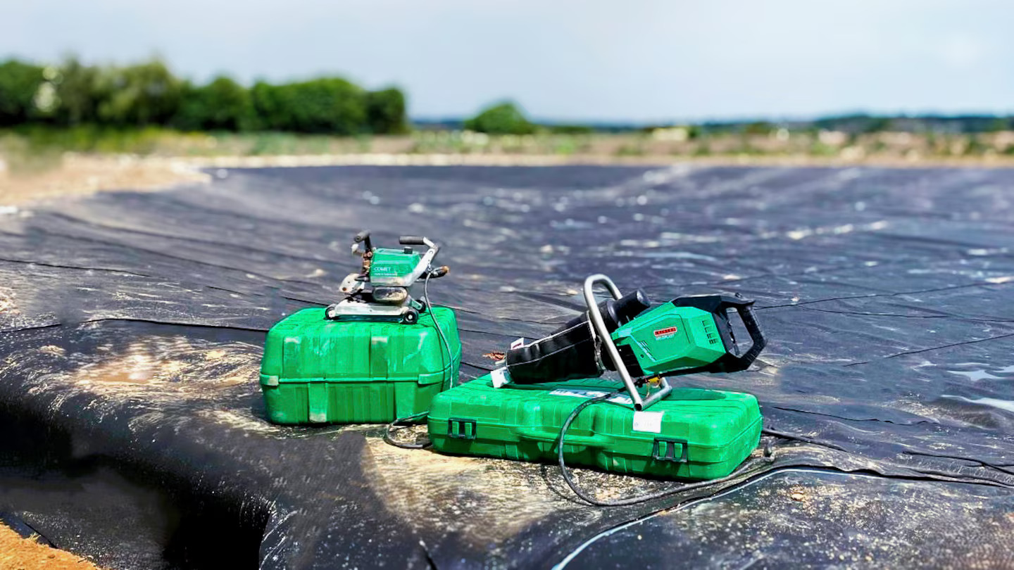 Ferramentas Leister COMET 700 e WELDPLAST 605 GEO posicionadas sobre geomembrana de PEAD durante a instalação de impermeabilização de lago ornamental no Reino Unido