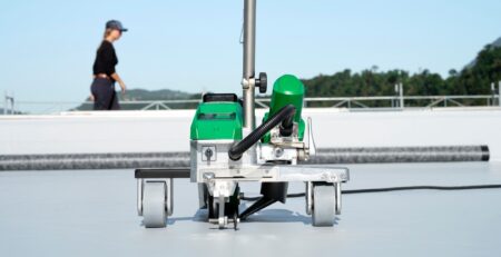 soldadora automática Leister VARIMAT 500 realizando soldagem contínua de membrana termoplástica em telhado comercial, assegurando desempenho consistente e alta eficiência operacional