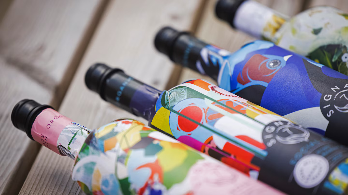 Garrafas Frugal Bottle de papel em close, com rótulos coloridos, mostrando a variedade de embalagens produzidas com precisão e aquecimento controlado Leister