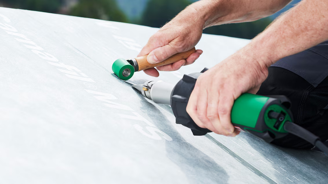 Soldagem manual de membrana de cobertura utilizando ferramenta de ar quente Leister TRIAC, com rolete para garantir acabamento uniforme e estanqueidade